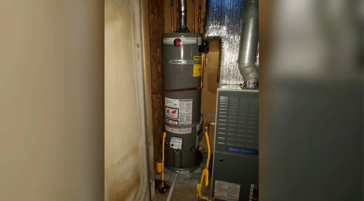 Gas water heater and a furnace side by side in a narrow closet with silver ducting overhead