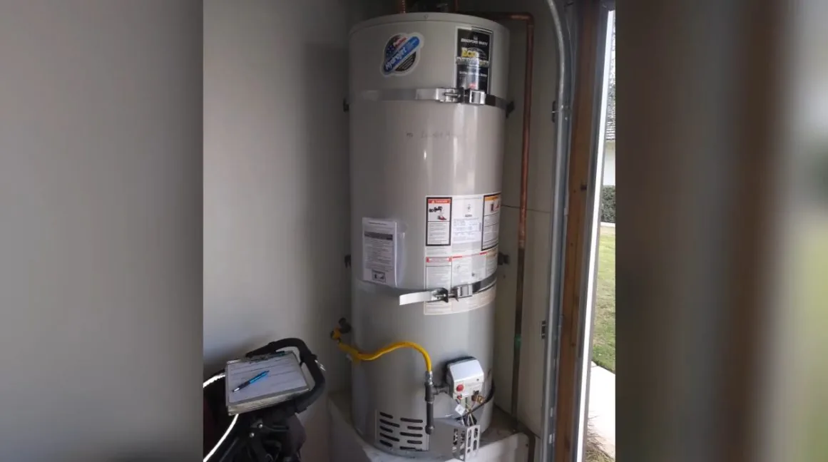 Gas water heater standing in a narrow utility closet with a vent pipe going up and a gas line at its base
