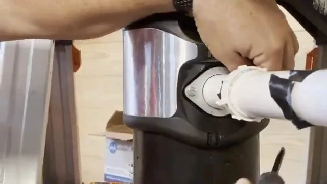 Hands connecting white PVC drain pipe to the outlet of a garbage disposal