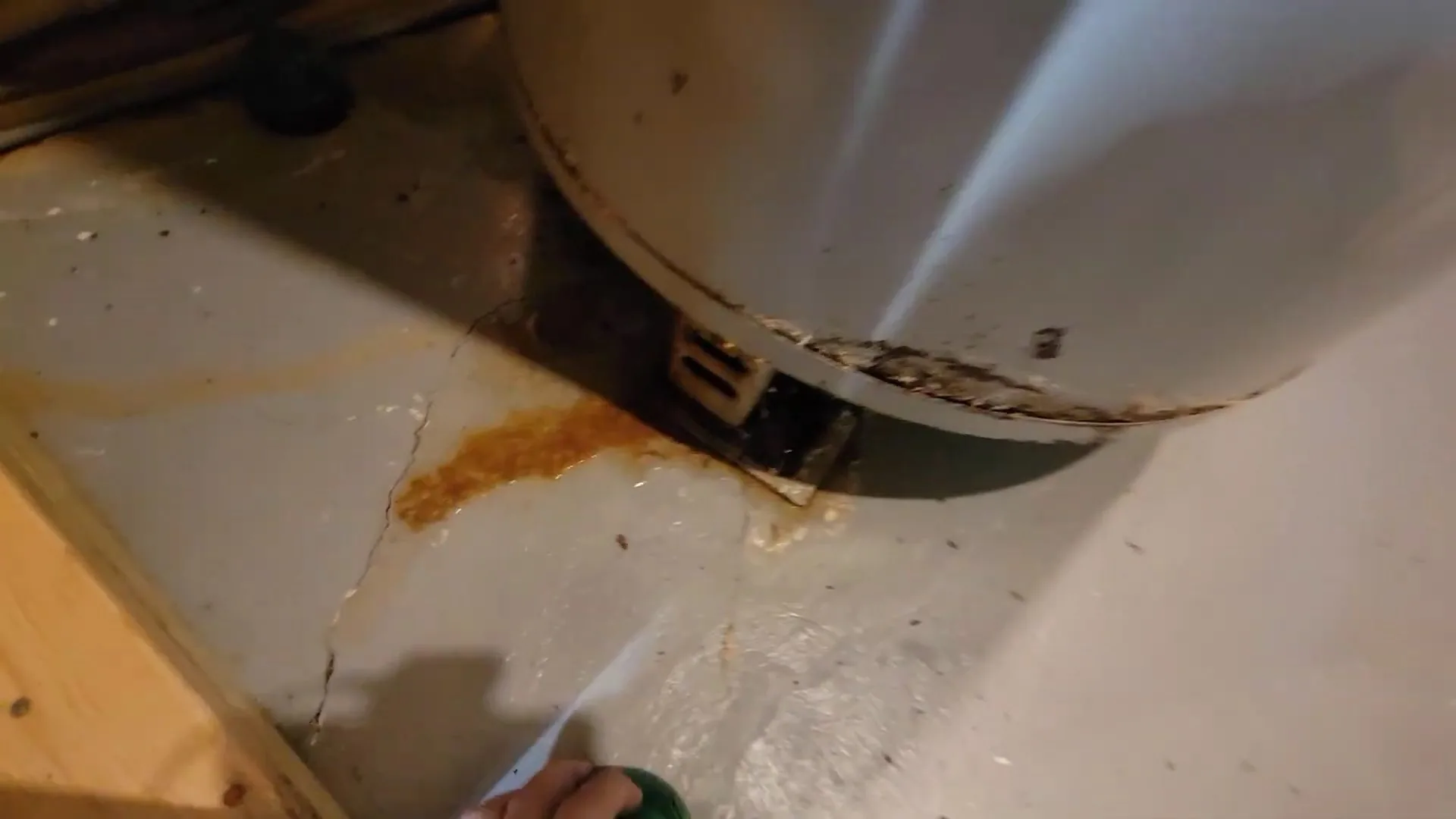 Orange rust stain on a floor beneath the base of a water heater